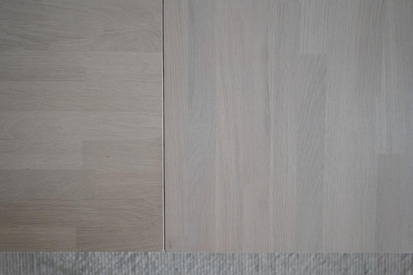Ljusgrå trägolv med synlig struktur och foder, närbild på laminat- eller parkettplankor