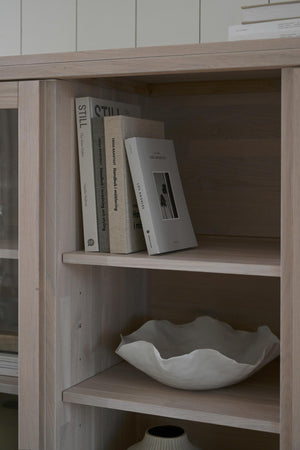 Bokhylla i ljust trä med böcker och dekorativ keramikskål i minimalistisk skandinavisk stil