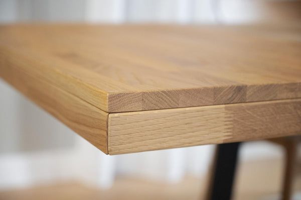 Närbild på bordskiva i massiv ek med synlig trästruktur och snickararbete i hörnet
