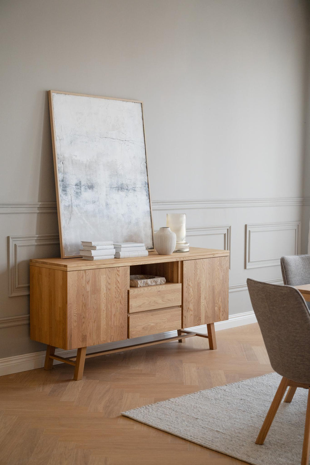 Sideboard i ljust trä med två skåpsdörrar, två lådor och öppen hylla på sneda ben
