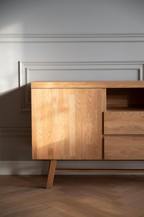 Skrivbord i ljust trä med skåp och lådor mot grå vägg med takpanel