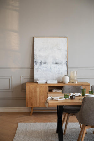 Ljust matrum med träbord, sideboard i ek, grå stolar och abstrakt konst på väggen