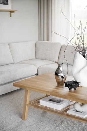 Ljust vardagsrum med beige soffa och soffbord i ek med hylla, dekorerat med vaser och böcker