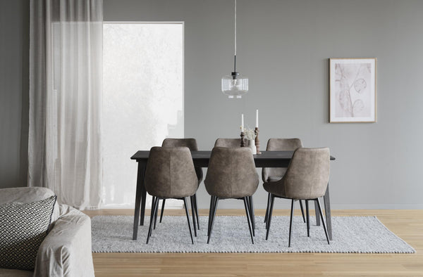 Matbord i svart trä med sex bruna sammetsstolar i modern matsal med grå väggar