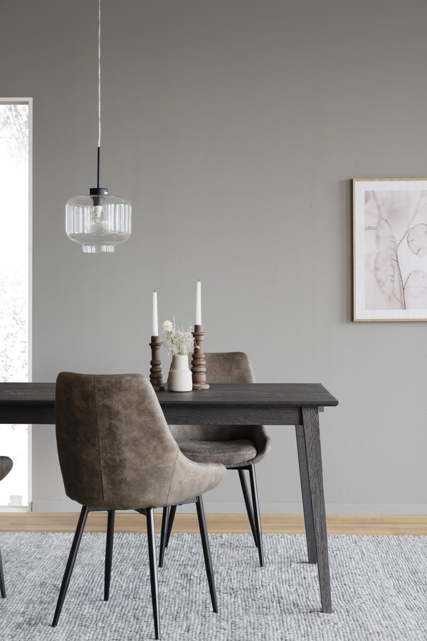 Matplats med grå träbord, bruna sammetsstolar, glaspendel och ljusa trädetaljer i minimalistisk nordisk stil