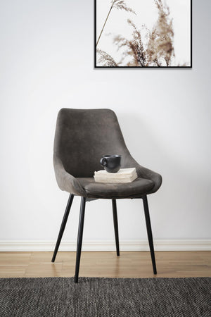 Grå sammetsstol med svarta ben och böcker med kaffekopp, minimalistisk inredning