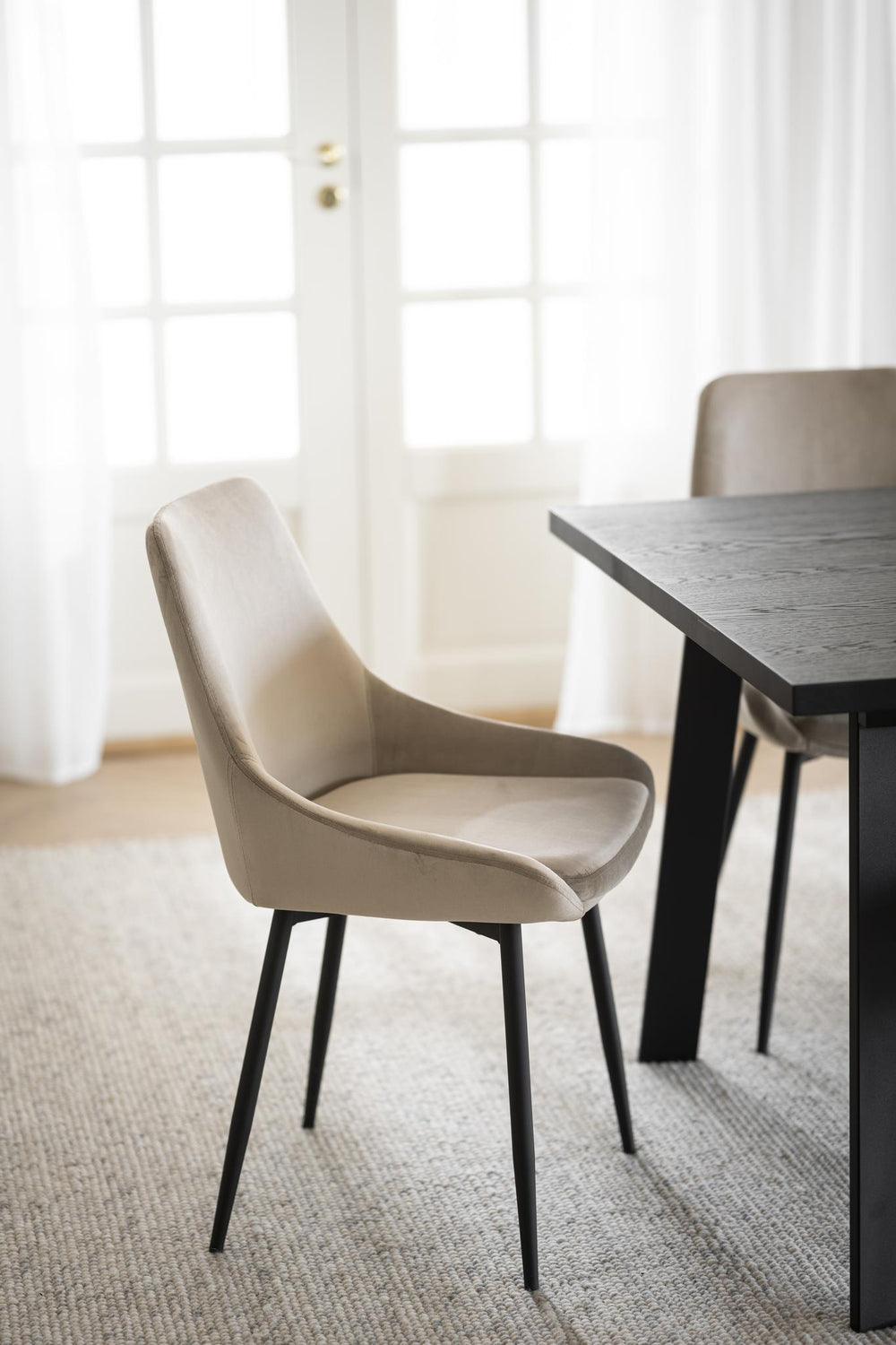 Beige matstol med sammet och svarta metallben i modern skandinavisk design