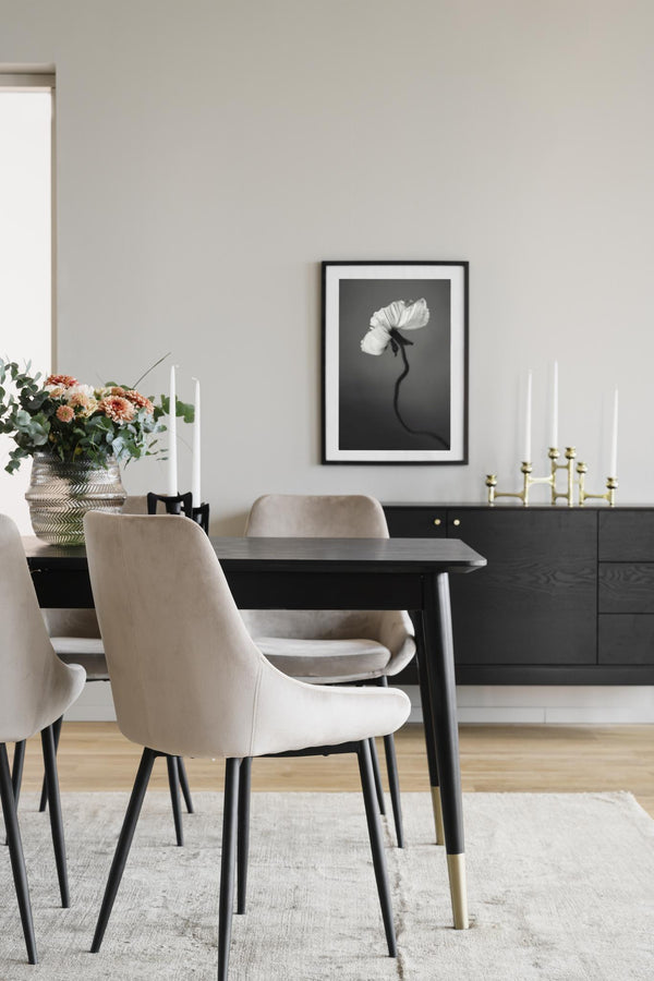 Elegant matplats med svart matbord, beige stolar och svartvit blomtavla på väggen