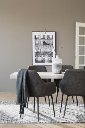Matgrupp med vita bordet och gråa stolar i modern skandinavisk matsal med tavla och textilier