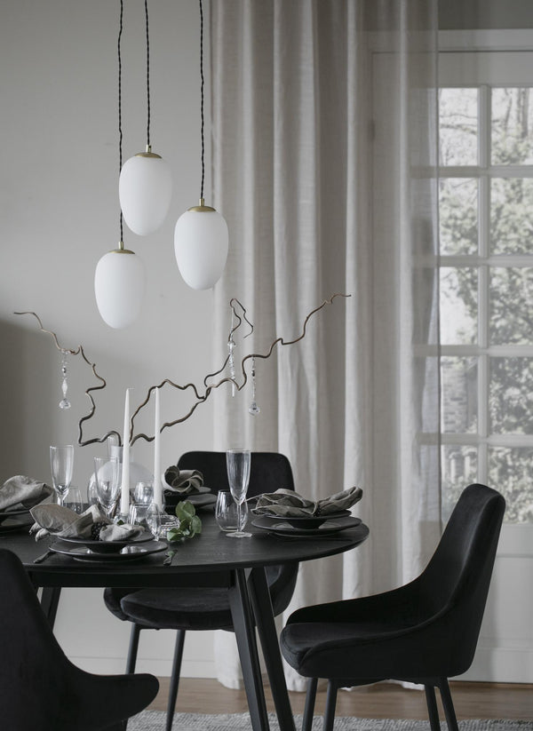 Stilren matplats med svarta stolar, runt bord och vita taklampor i skandinavisk design