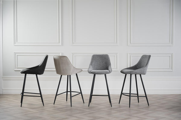 Fyra moderna barstolar i svart, beige och grå mot vit vägg med spegelpaneler