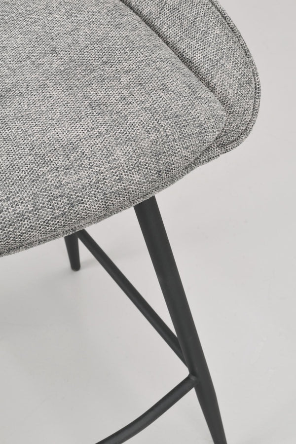 Närbild på grå stoppad stolsits med svarta metallben i modern design