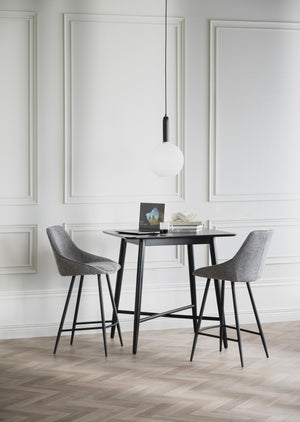 Grå barstolar vid svart barbord i modernt rum med vit väggpanel och designlampa