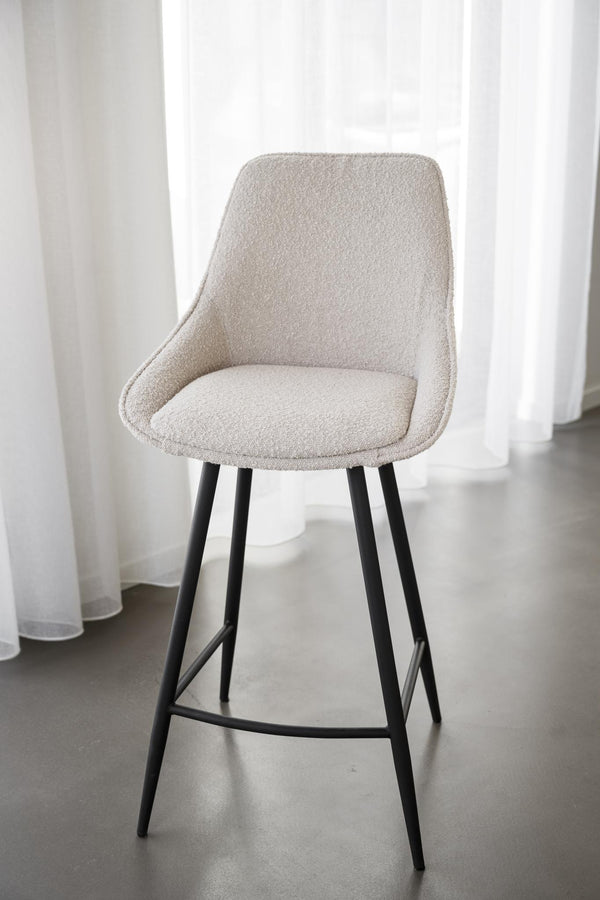 Barstol med beige klädsel och svarta ben i modern skandinavisk design