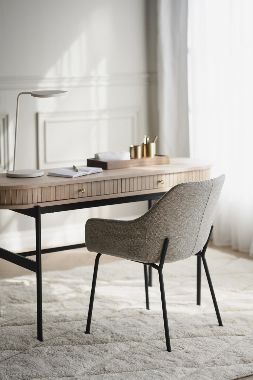 Grå stoppad stol med svarta metallben, modern design med armstöd och kurvad rygg