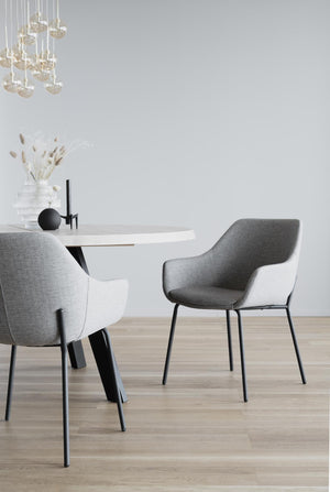 Grå matbordsstolar med armstöd runt vitt runt matbord i modern skandinavisk matsal