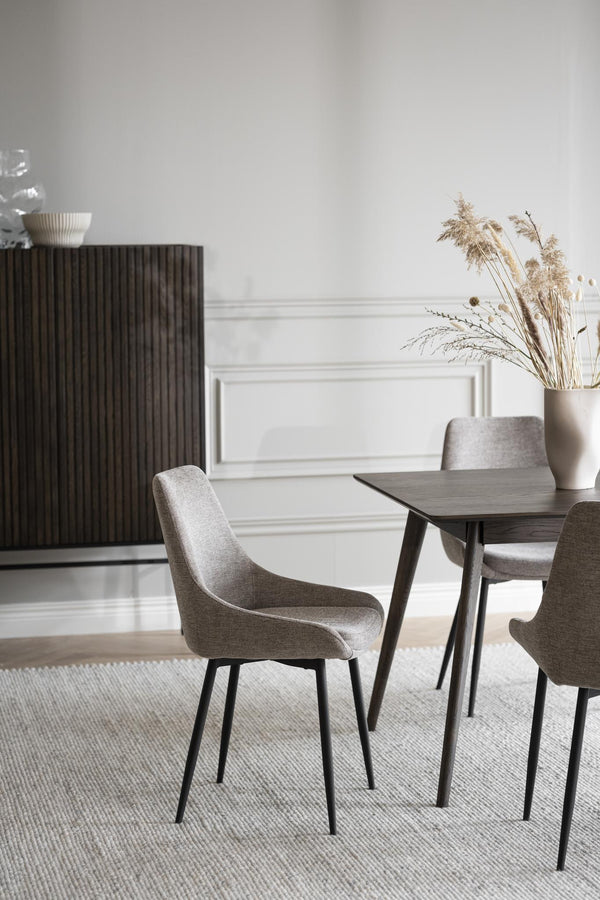 Moderna grå matstolar med svarta ben runt matbord i minimalistisk matsalsinteriör med beige väggdekor