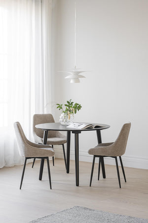 Rund matgrupp med svarta ben och fyra gråbeige stolar under modern taklampa i minimalistisk matsal