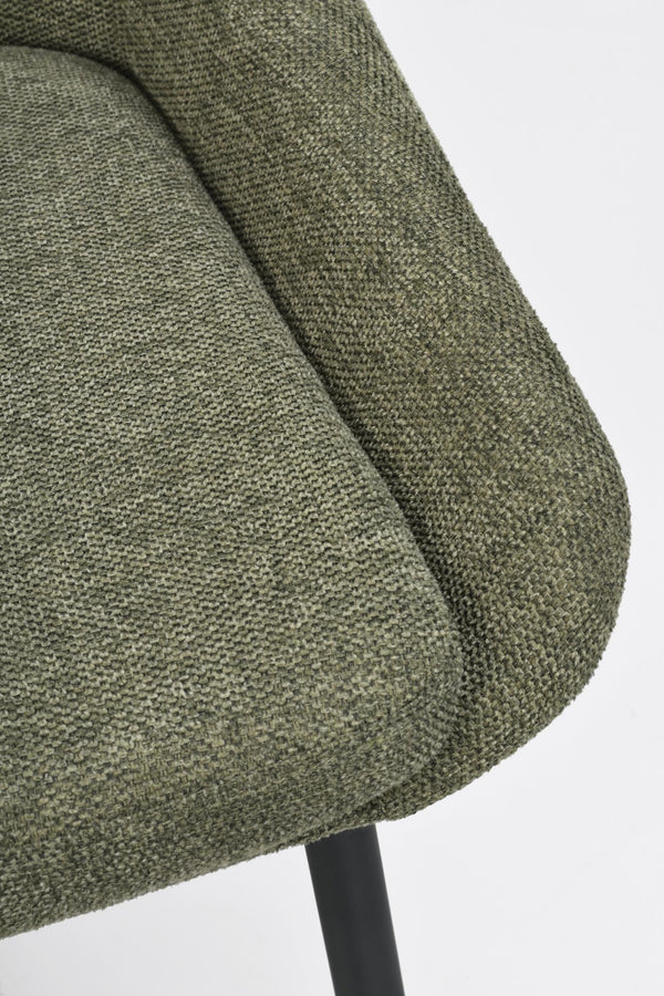 Närbild på grön stol med textilfärgad klädsel och svarta ben