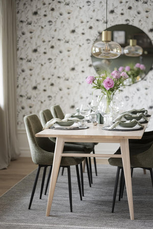 Matbord i ljust trä med gröna stolar, uppdukat med tallrikar, glas och rosa blommor i vas