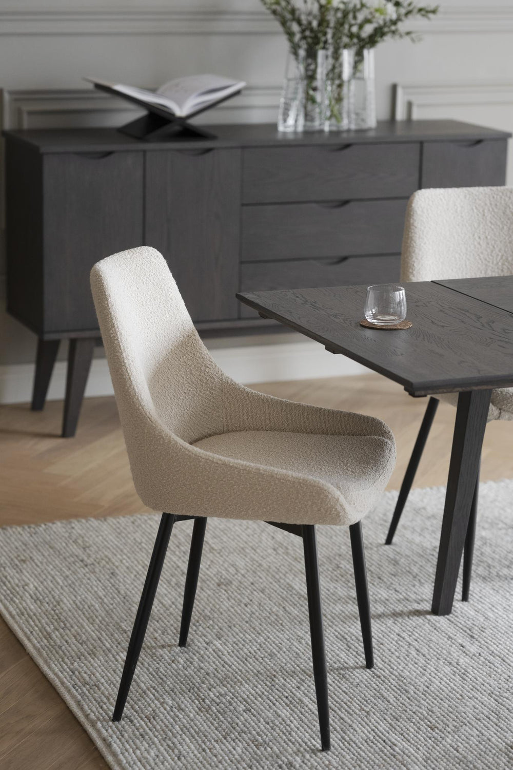 Beige matstol med hög rygg och svarta metallben, modern skandinavisk design