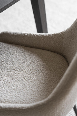 Närbildsbild på beige fåtölj med mjuk klädsel och modern design vid fönster