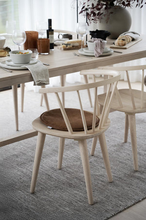 Ljust matbord i trä med stolar, dukade tallrikar, glas och servetter i skandinavisk minimalistisk stil