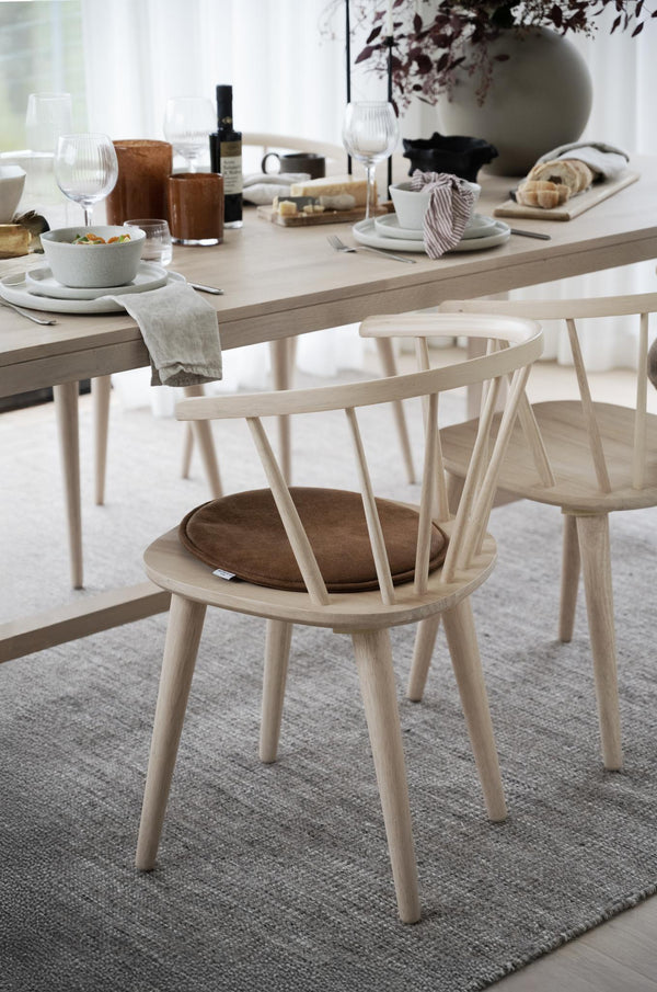 Ljust matbord i trä med stolar, dukade tallrikar, glas och servetter i skandinavisk minimalistisk stil