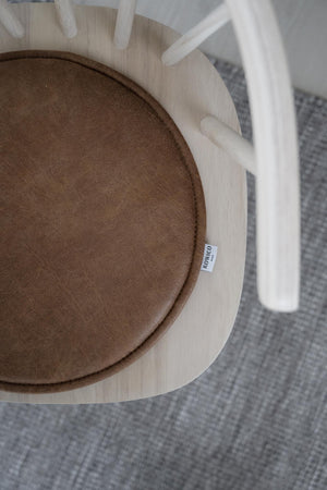 Brun stoldyna i sammet på trästol med vit etikett från POMP&CO