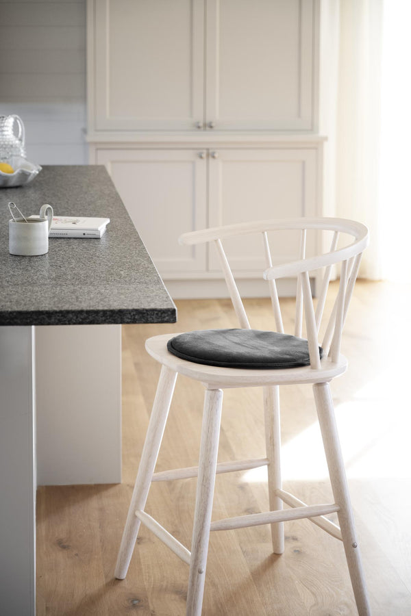 Vit barstol med spjälor i ryggstöd och grå sits-dyna vid köksbänk med grå bänkskiva