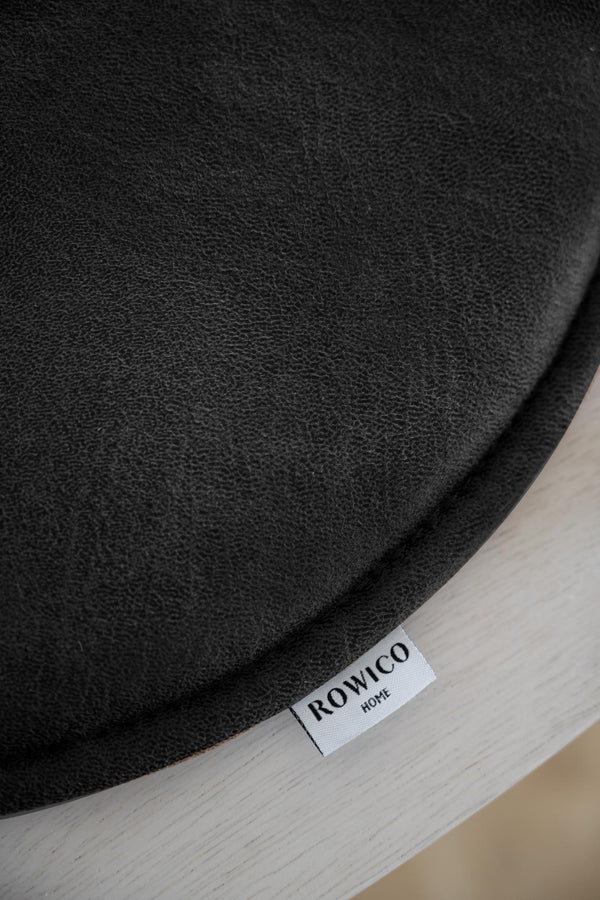 Närbild av svart sängkappa med Rowico Home-etikett på ljust trä