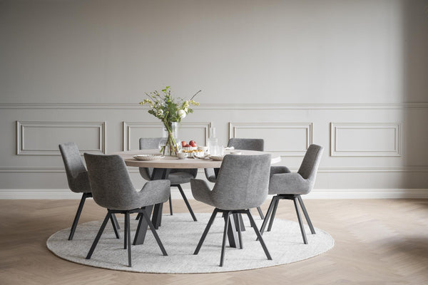 Matgrupp med runt bord i ek och sex grå stolar på ljus rund matta i elegant matsal