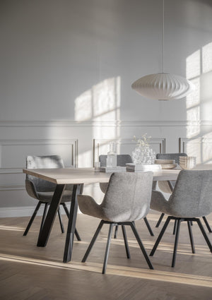 Matgrupp med ljust träbord och grå stolar i modern skandinavisk matsal med vit taklampa