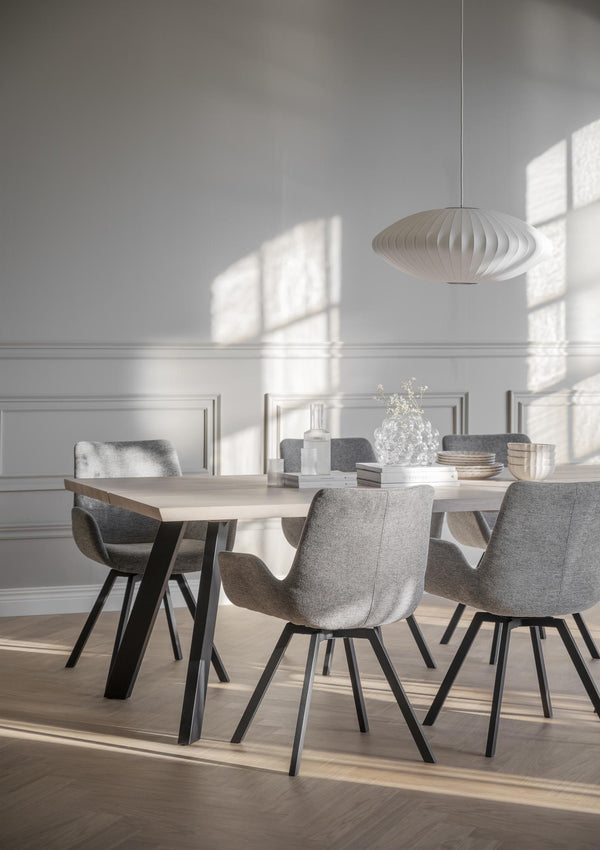 Matgrupp med ljust träbord och grå stolar i modern skandinavisk matsal med vit taklampa