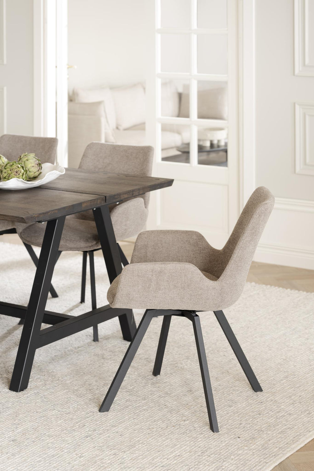 Beige stol med armstöd och svarta träben, frontvy mot vit bakgrund