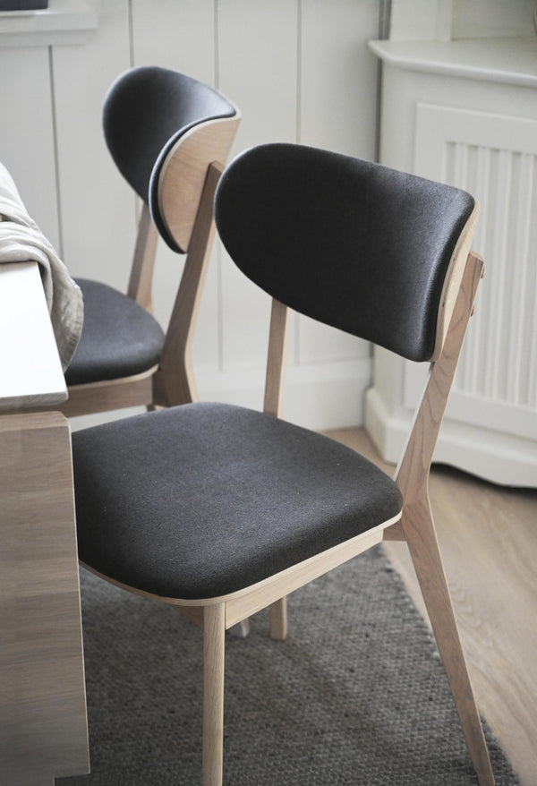 Moderna matstolar med svart klädsel och ljust trästomme i skandinavisk design