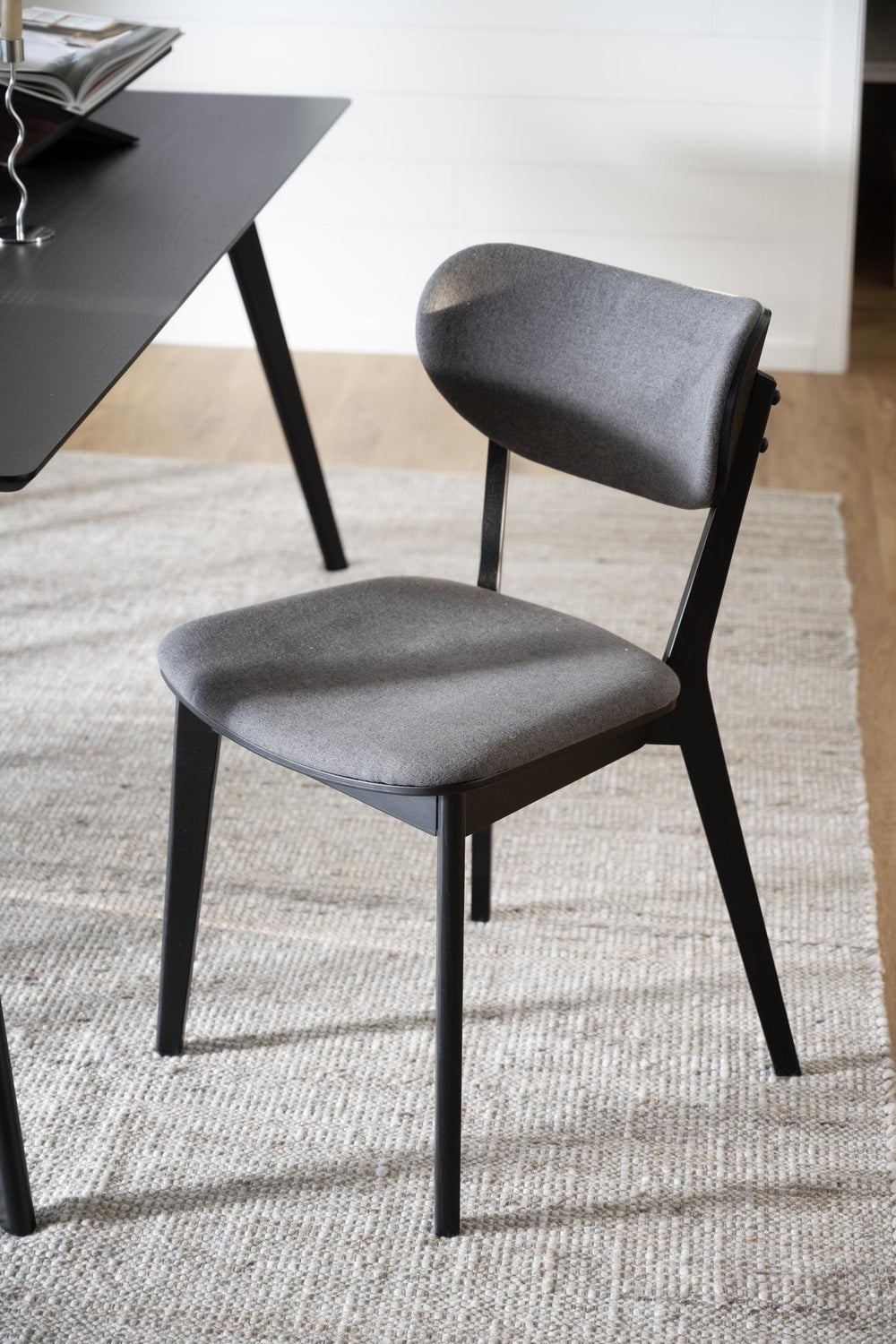 Svart stol med grå stoppad sits och ryggstöd, moderna träben i skandinavisk design