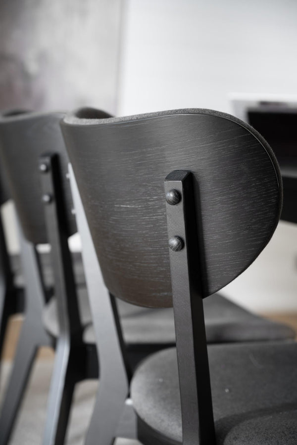 Närbild på svart träkarmstol med metallbeslag och synlig trästruktur i modern skandinavisk design