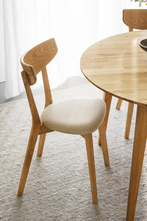 Matstol i ek med stoppad sits i beige tyg vid runt matbord