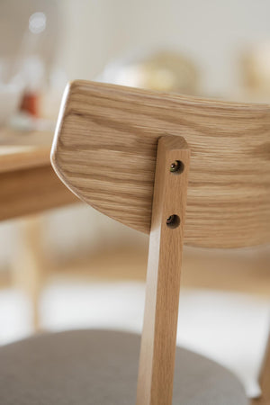 Närbild på stol i ljust trä med synliga skruvar i ryggstödet, skandinavisk design