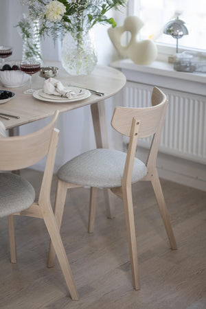 Ljusa trässtolar med stoppad sits vid matbord i skandinavisk stil med elegant dukning