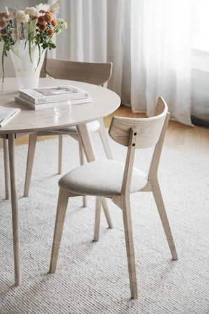 Ljus ekstol med stoppad sits vid runt matbord i skandinavisk stil
