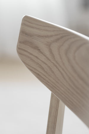 Närbild på ryggstöd och ben av trästol i ljust trä med synlig trästruktur och mjuka rundade kanter