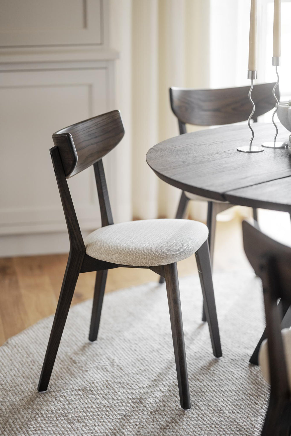 Matstol i mörkbetsad ek med beige stoppad sits och böjd rygg, skandinavisk design