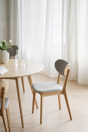 Matbord i ljust trä med stol i grå klädsel och vita tulpaner i vas, skandinavisk inredningsstil