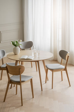 Runt matbord i ljust trä med fyra stolar med grå klädsel i skandinavisk stil