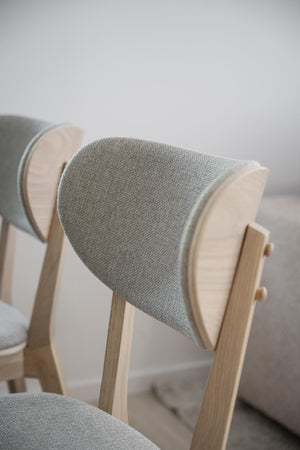 Fåtölj med grå textilklädsel och ljust trästomme i skandinavisk design