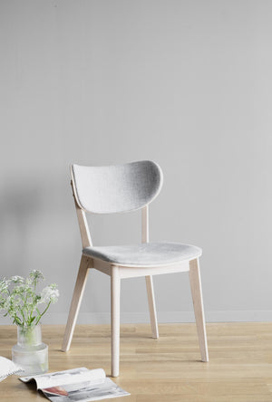 Vit stol med ljusgrå stoppad sits och rygg i skandinavisk design på trägolv