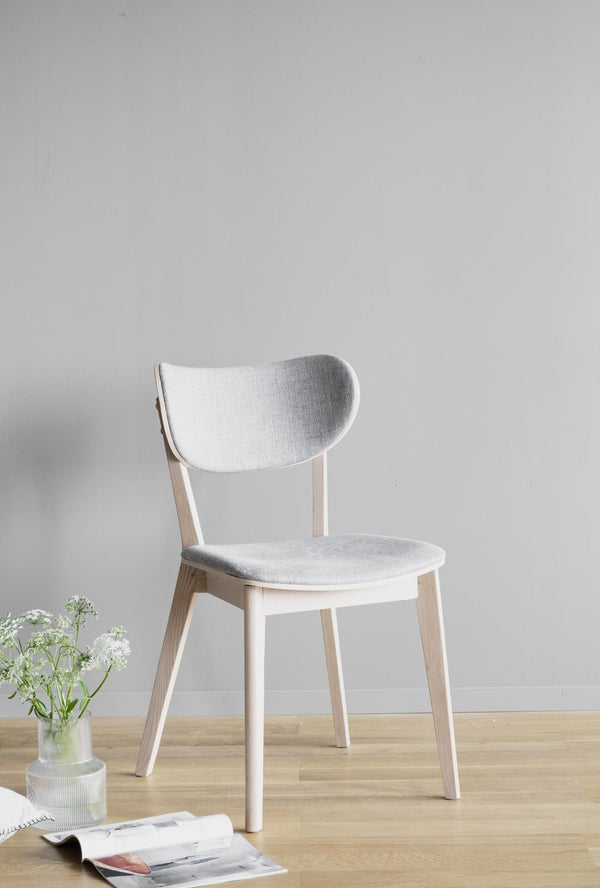 Vit stol med ljusgrå stoppad sits och rygg i skandinavisk design på trägolv