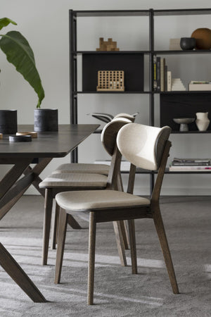 Moderna matstolar i trä med beige klädsel vid svart matbord i skandinavisk matsal